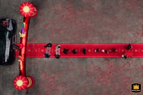 Flowers fly through the air during the flower toss at a hotel in Fujian, while a sweeping drone view captures the entire red carpet entourage winding its way the car.